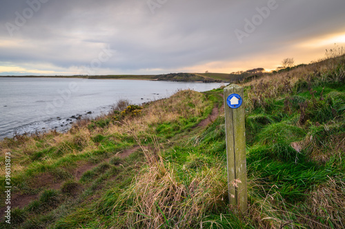 Signpost for Northumberland Coast Path, joined here with St Oswalds Way, on the shoreline at Howick on the Northumberland coast AONB photo