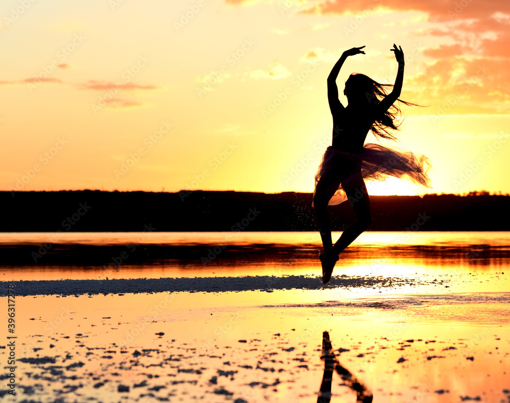 Tender girl young ballerina in pink transparent in a graceful jump on the lake at sunset. Tender girl young ballerina in pink transparent in a graceful jump on the lake at sunset.