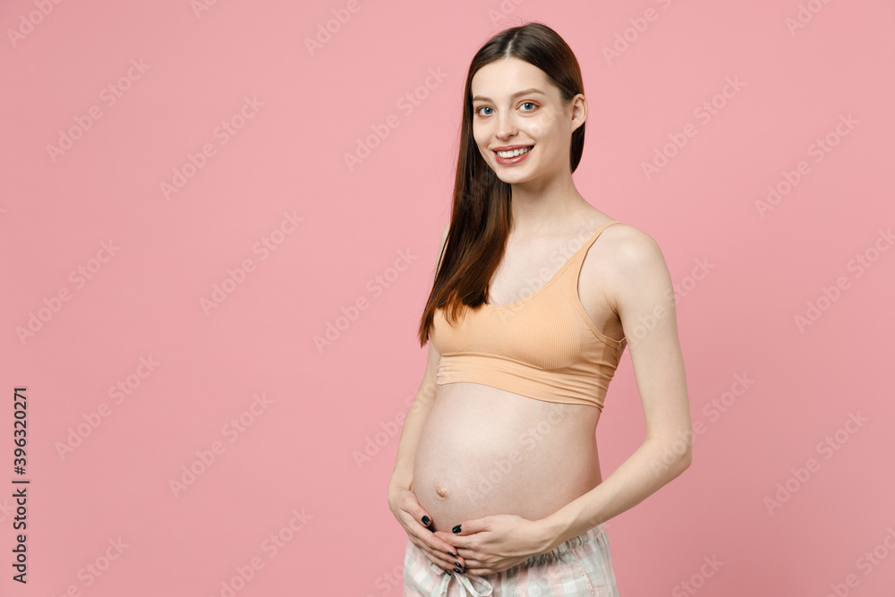 Happy young pregnant woman future mom in basic top stroking keeping hands on big belly stomach tummy with baby isolated on pastel pink background studio. Maternity family pregnancy gynecology concept. Happy young pregnant woman future mom in basic top stroking keeping hands on big belly stomach tummy with baby isolated on pastel pink background studio. Maternity family pregnancy gynecology concept.