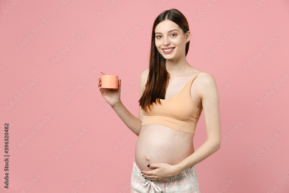 Pregnant woman future mom in top with belly stomach tummy with baby hold applying cream for stretch marks striae isolated on pink background studio Maternity family pregnancy expectation concept Pregnant woman future mom in top with belly stomach tummy with baby hold applying cream for stretch marks striae isolated on pink background studio Maternity family pregnancy expectation concept