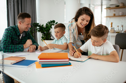 Parents helping the kids with their homework. Litlle boys learning at home..