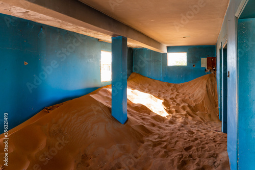 Neglected house interior with blue walls buried in the sand in Al Madam ghost village in United Arab Emirates.