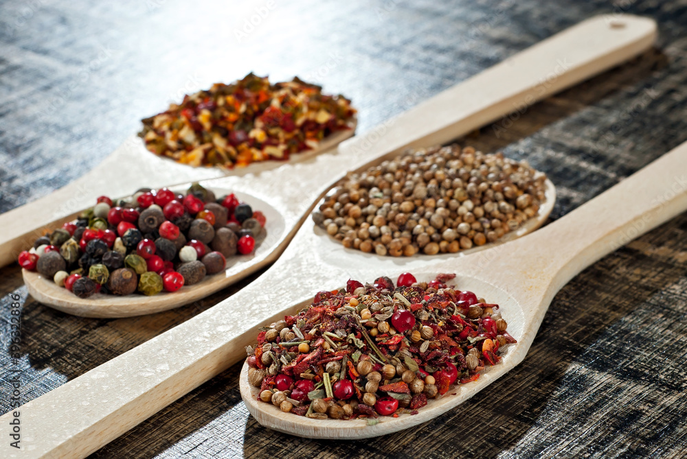 A mixture of various spices in a wooden spoon. Spices and seasonings on an old shabby board. Mix on a pile close up. A mixture of various spices in a wooden spoon. Spices and seasonings on an old shabby board. Mix on a pile close up.