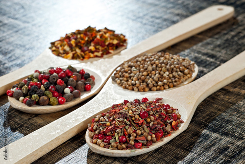 A mixture of various spices in a wooden spoon. Spices and seasonings on an old shabby board. Mix on a pile close up.