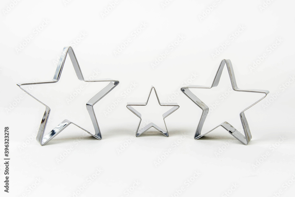 Three metal cookie cutters in the shape of a star of different sizes on a white background. Family concept - mom, dad and child. Three metal cookie cutters in the shape of a star of different sizes on a white background. Family concept - mom, dad and child.