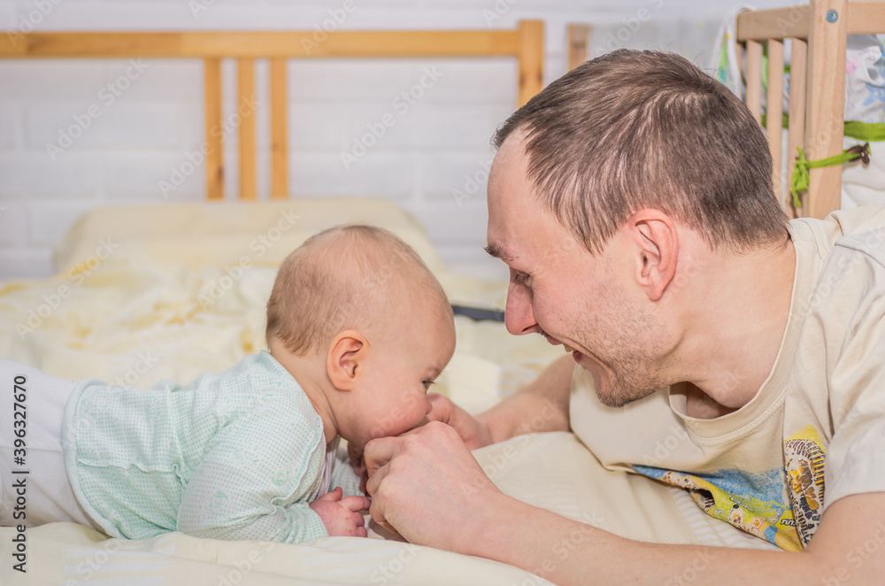 Little baby and dad look at each other while lying on the bed Little baby and dad look at each other while lying on the bed