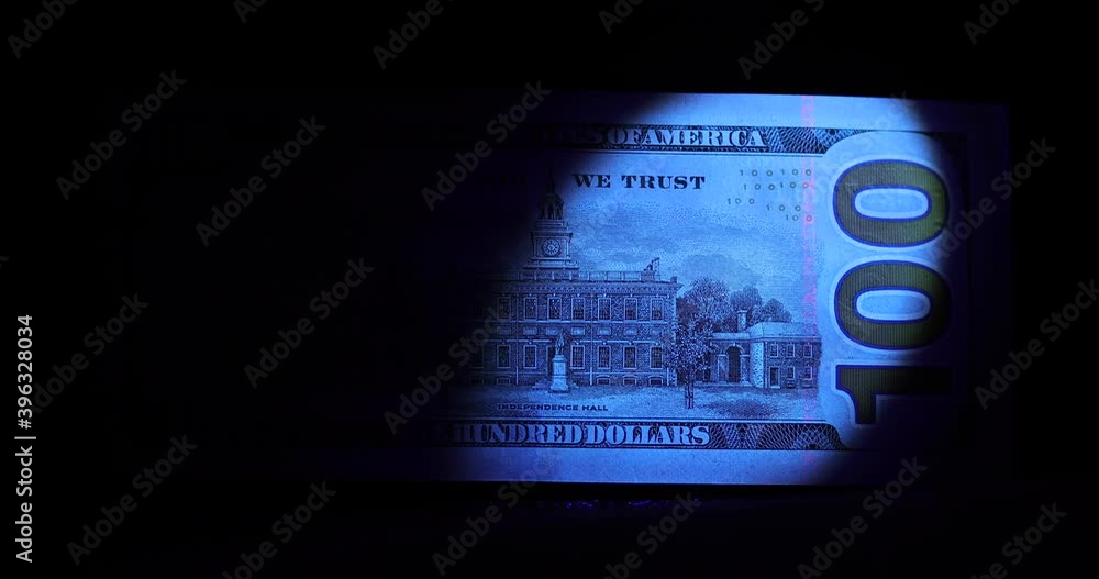 One hundred dollar banknote in the ray of ultraviolet light with security signs watermark and other protection against fraud One hundred dollar banknote in the ray of ultraviolet light with security signs watermark and other protection against fraud