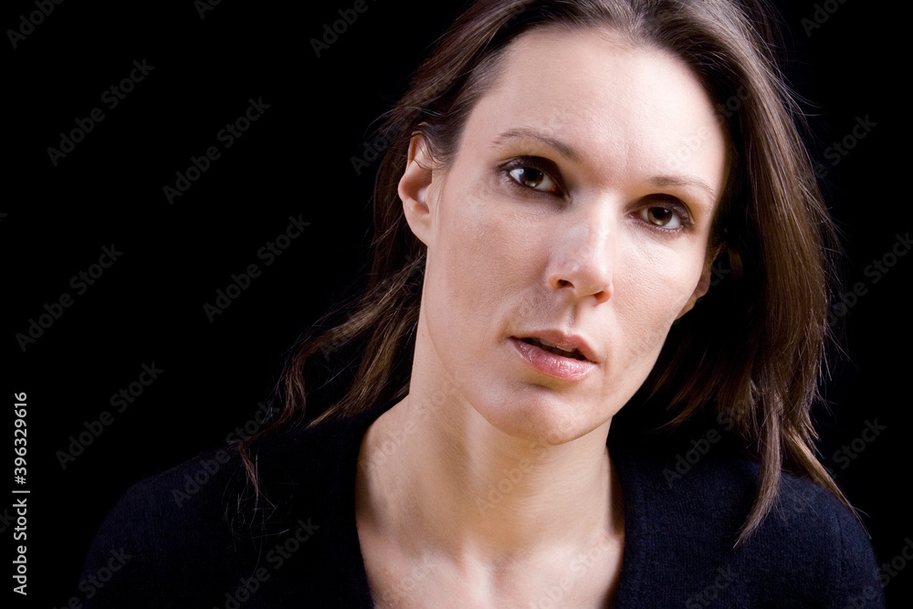 Dark studio portrait of a serious brunette. Studio portrait isolated on black background. Dark studio portrait of a serious brunette. Studio portrait isolated on black background.