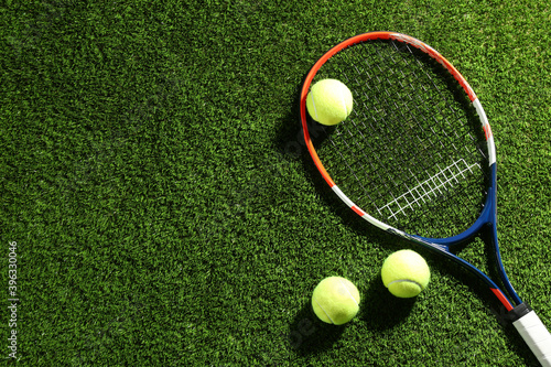 Tennis racket and balls on green grass, flat lay. Space for text © New Africa