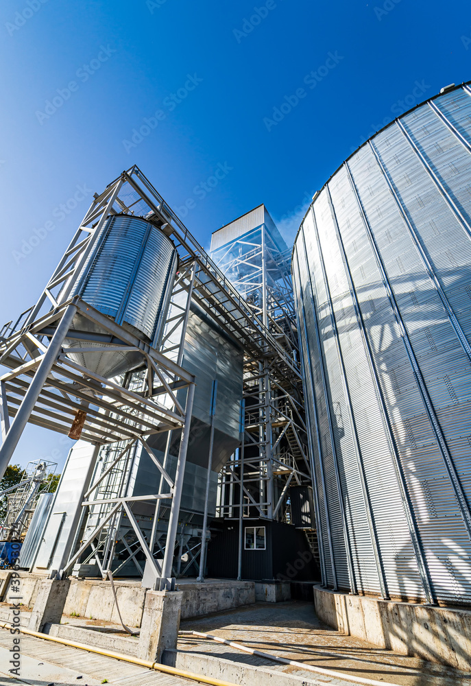 Metal grain elevators on modern factory. Crop storage in factory. Selective focus on steel constructions and technic.
