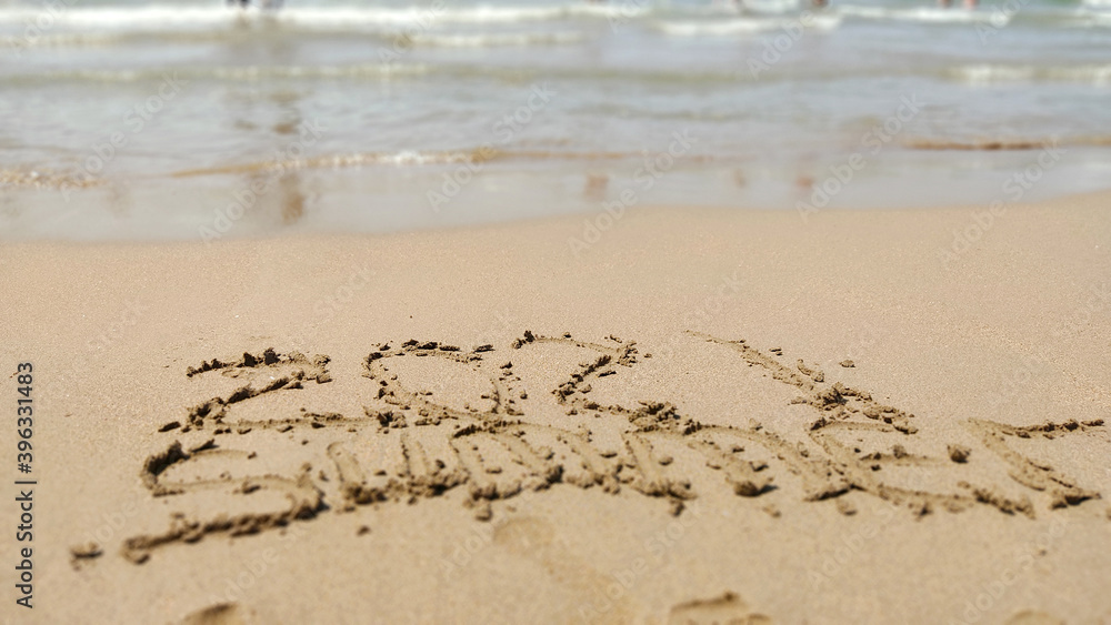 word handwritten summer 2021 on yellow sandy beach word handwritten summer 2021 on yellow sandy beach