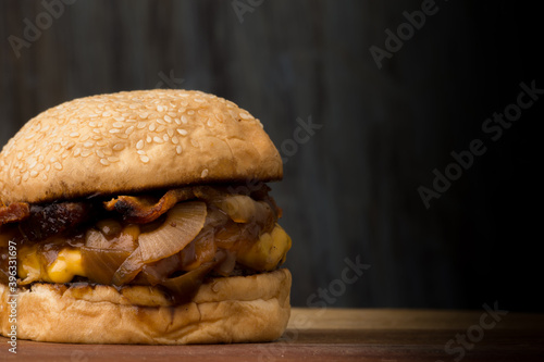 bacon burger with onions and juicy cheedar on wooden table. Space for text