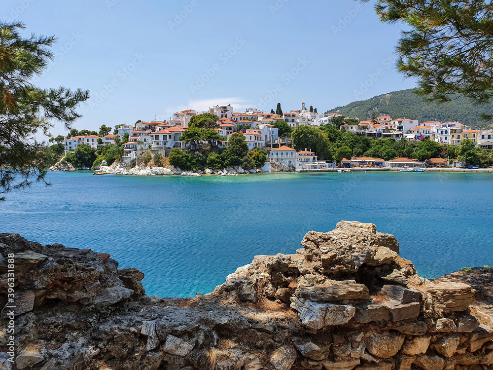 Fototapeta premium View through ruins of stones to the old part of the town of Skiathos on Skiathos island, Greece.