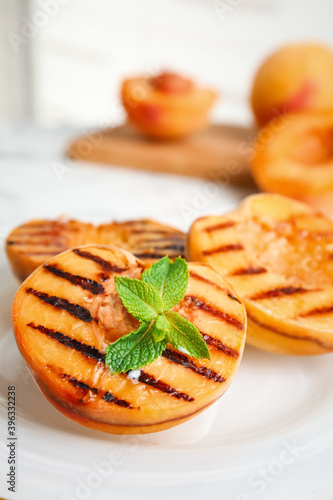Delicious grilled peaches with mint on plate, closeup