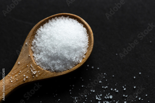 salt in a wooden spoon on black background. Selective focus
