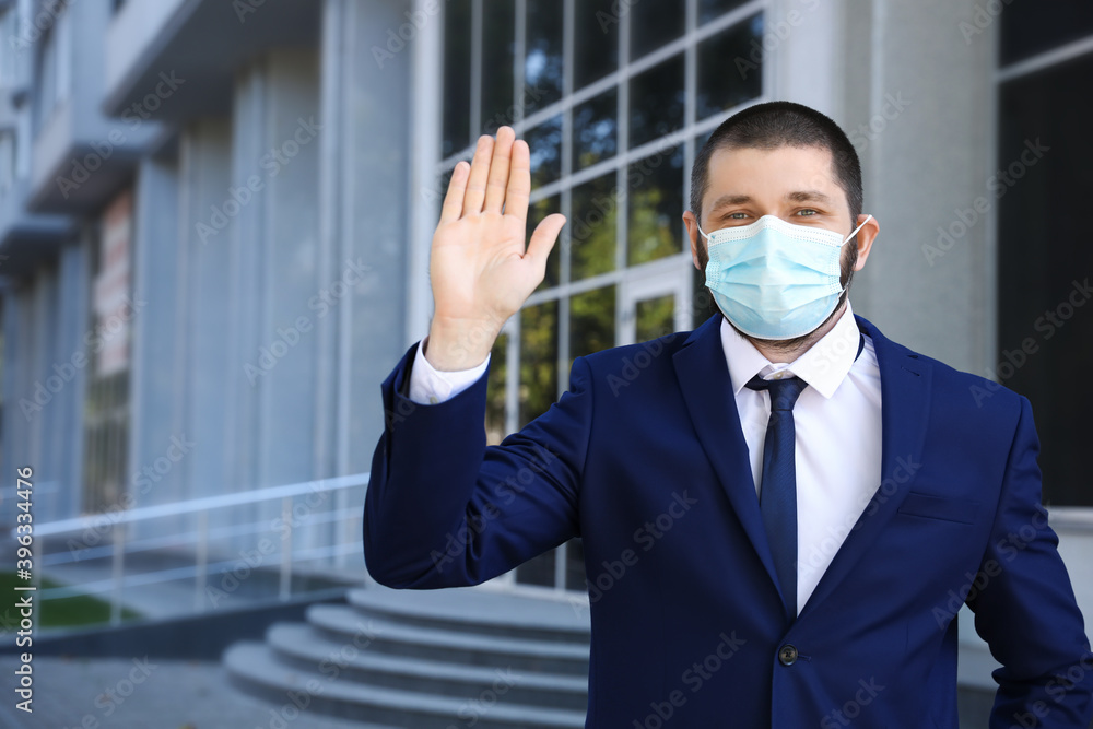Man in protective face mask showing hello gesture outdoors. Keeping social distance during coronavirus pandemic Man in protective face mask showing hello gesture outdoors. Keeping social distance during coronavirus pandemic