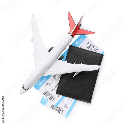 Toy airplane and passport with tickets on white background, top view