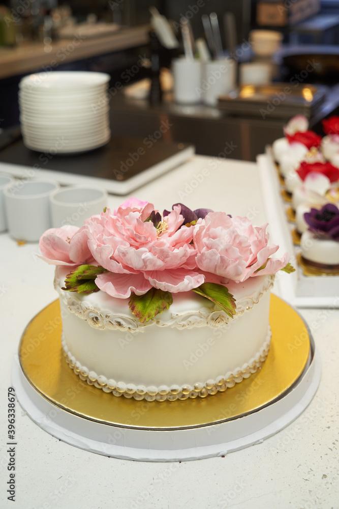 White cake with pink flowers on golden tray White cake with pink flowers on golden tray