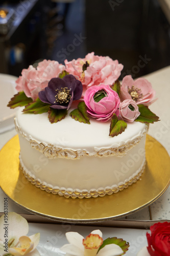 White cake with pink flowers on golden tray