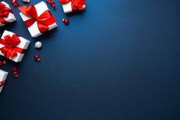 Merry Christmas and Happy Holidays greeting card, frame, banner. New Year. Noel. Christmas ornaments and gift box on blue background top view. Winter xmas holiday theme. Flat lay