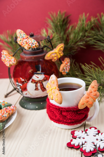 On a light wooden background  a Cup of tea and cookies in the form of butterflies with Christmas decorations . Close-up  copy space