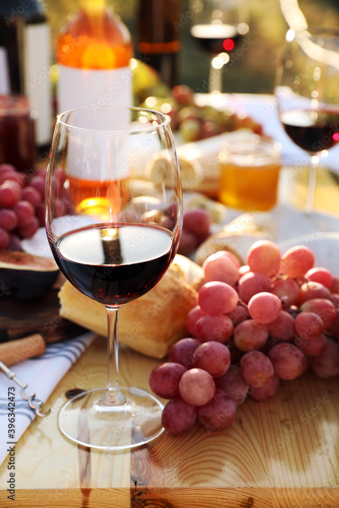 Red wine and snacks served for picnic on wooden table outdoors Red wine and snacks served for picnic on wooden table outdoors