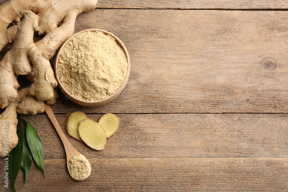 Fresh ginger root, powder and leaves on wooden table, flat lay. Space for text Fresh ginger root, powder and leaves on wooden table, flat lay. Space for text