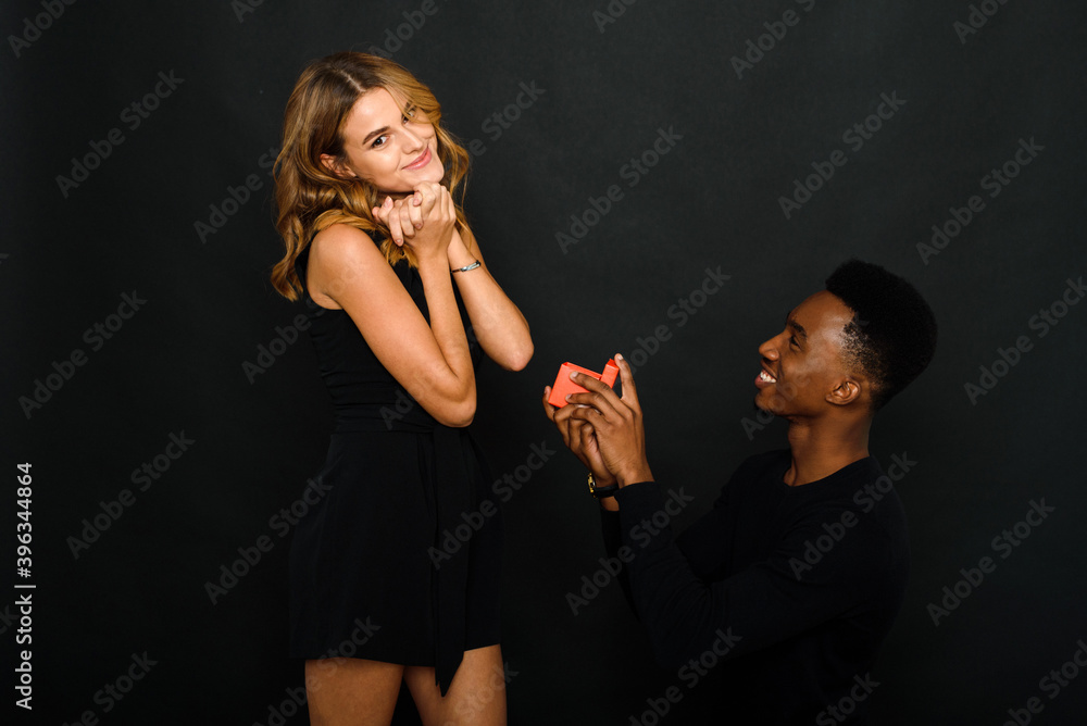 A young black man proposes to his Caucasian girlfriend while standing on one knee. Multi-ethnic couple A young black man proposes to his Caucasian girlfriend while standing on one knee. Multi-ethnic couple