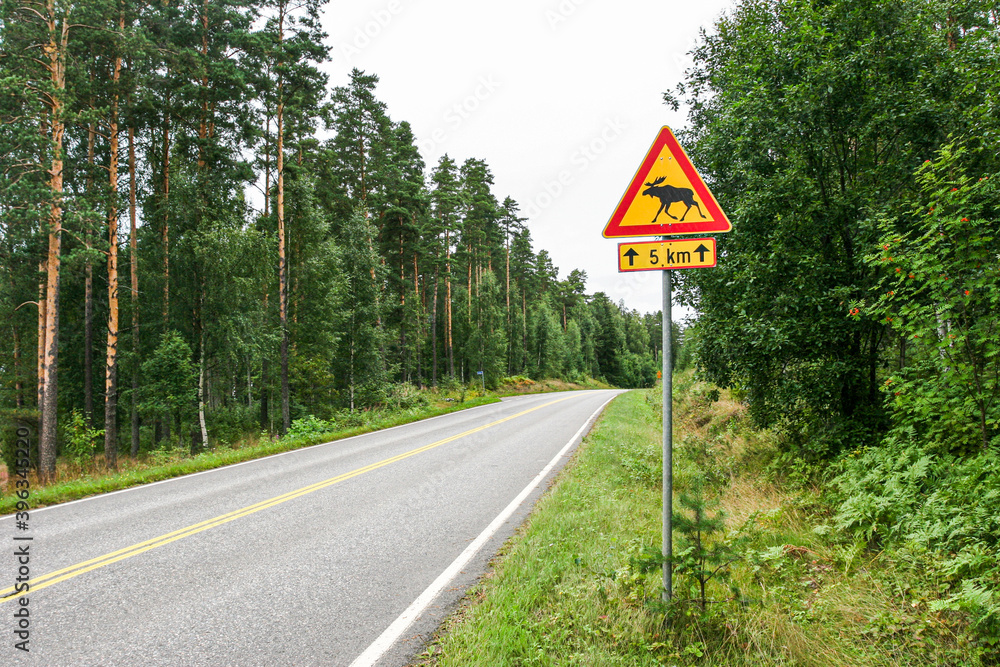 Landsctraße in Finnland mit Warnschild vor Elch Landsctraße in Finnland mit Warnschild vor Elch