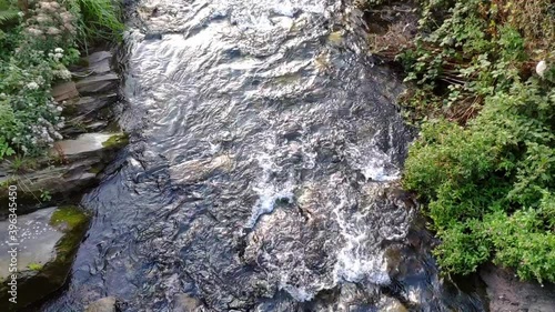 River in Boscastle village , Cornwall (England).Stream of water flowing. Shallow water and rocks are seen below. Lime stone on the sides. Some sunlight from sunset. photo