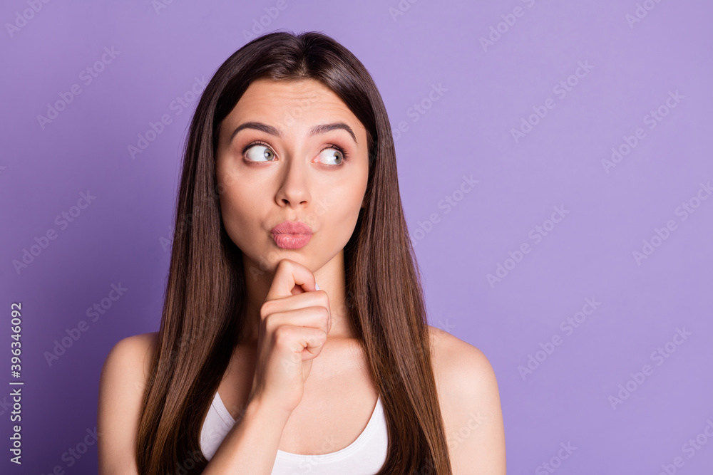 Photo portrait of pouting thinking girl touching face chin with finger looking at blank space isolated on vivid purple colored background Photo portrait of pouting thinking girl touching face chin with finger looking at blank space isolated on vivid purple colored background