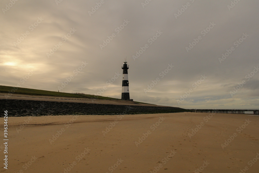 a coast landscape with a large sand beach and a lighthouse at the seawall and a grey sky in winter in breskens a coast landscape with a large sand beach and a lighthouse at the seawall and a grey sky in winter in breskens