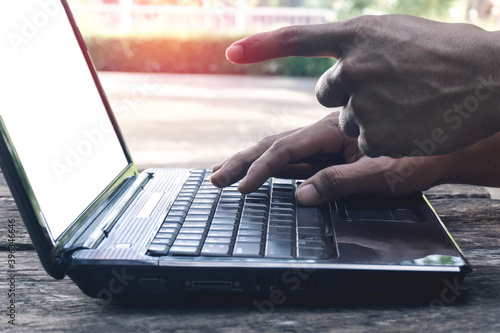 Hand Person working pointing to screen white mockup and using on a laptop computer for freelance with input keyboard for online blogger job to black computer on a wooden table at home.