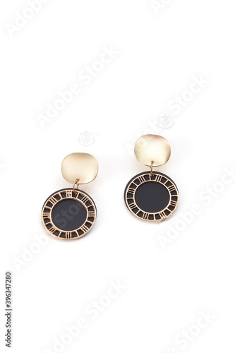 Subject shot of two earrings with pendants. Each earring is made as curved golden disc with hanging black plate with fretted golden rim. The pair of earrings is isolated on the white backdrop.