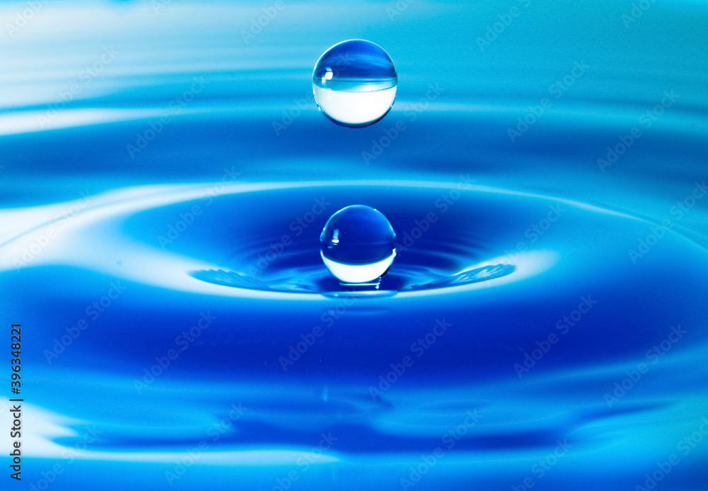 Dark blue water droplets splash in the water surface close up. Creating a perfect water wave Dark blue water droplets splash in the water surface close up. Creating a perfect water wave