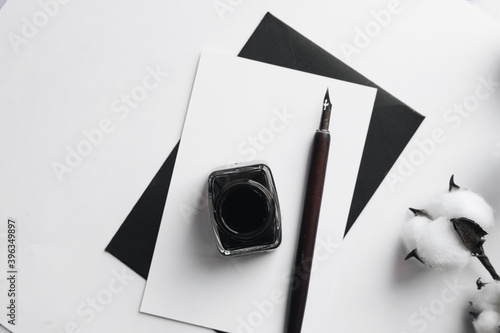 Set of vintage dip pen, inkpot and blank paper sheet with envelope on white wooden table photo