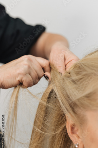 Girl in a hair salon, stylist make hair style for client in Woman's Hair In Hairdresser Salon, close view of hands, spikelet 