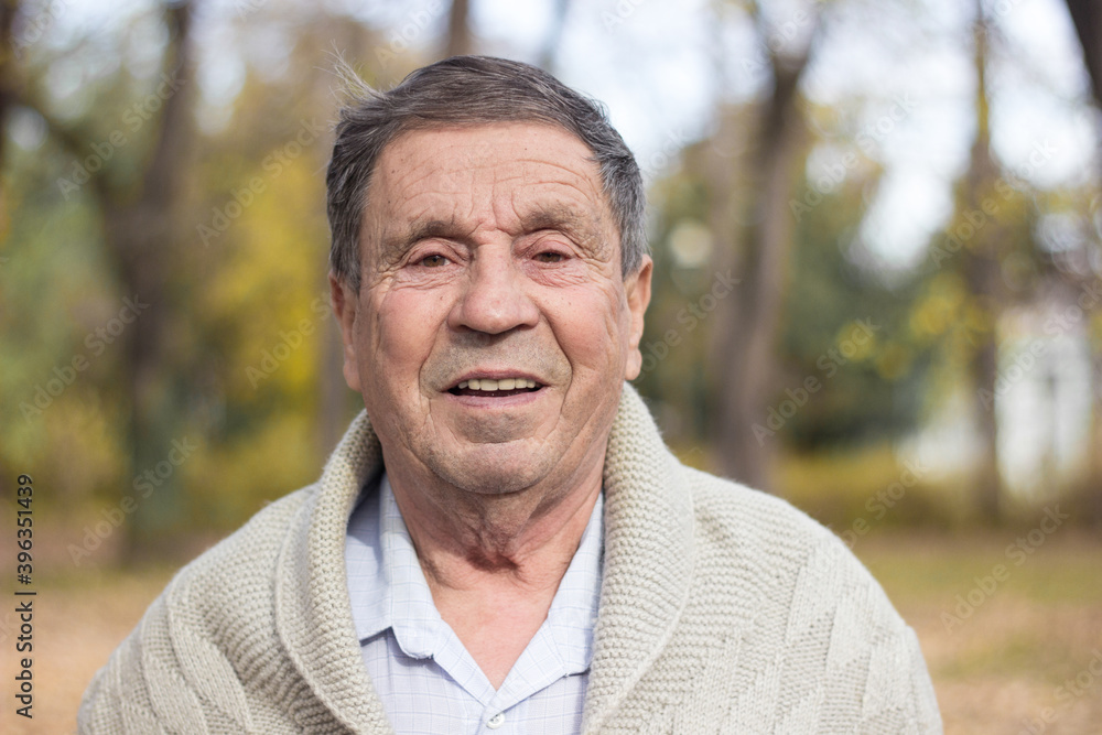Portrait of happy senior man smiling, in the public park, outdoors. Old man relaxing outdoors and looking at camera. Portrait of elderly man enjoying retirement Portrait of happy senior man smiling, in the public park, outdoors. Old man relaxing outdoors and looking at camera. Portrait of elderly man enjoying retirement