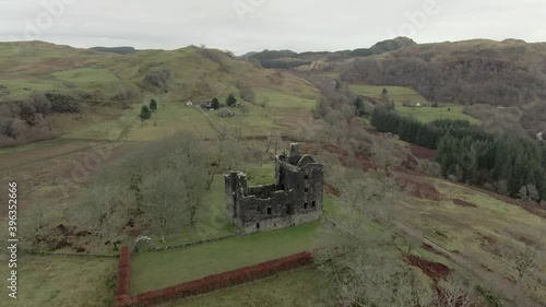 Aerial view of Carnasserie Castle ruins on an overcast day in Argyll and Bute, Scotland. Circling left to right around the castle whilst moving away. photo