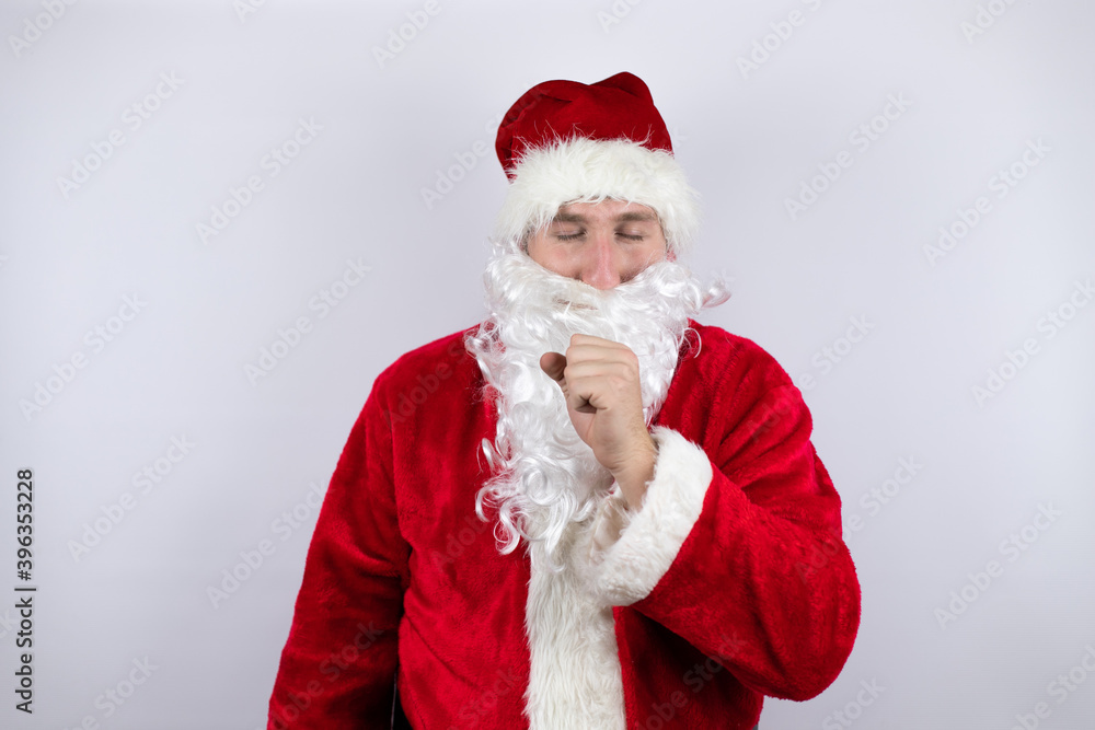 Man dressed as Santa Claus standing over isolated white background with his hand to his mouth coughing Man dressed as Santa Claus standing over isolated white background with his hand to his mouth coughing