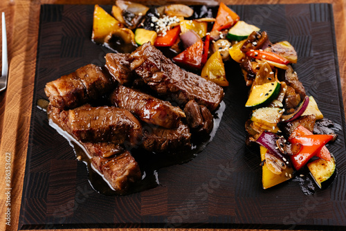 marbled beef steak with vegetables and sauce on a black backgrou photo