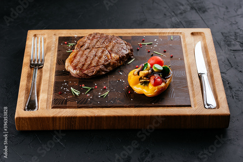 marbled beef steak with vegetables and sauce on a black backgrou photo