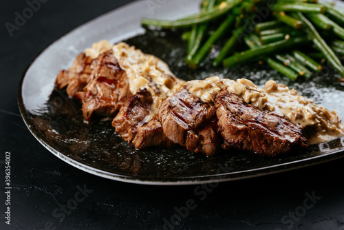 marbled beef steak with vegetables and sauce on a black backgrou photo