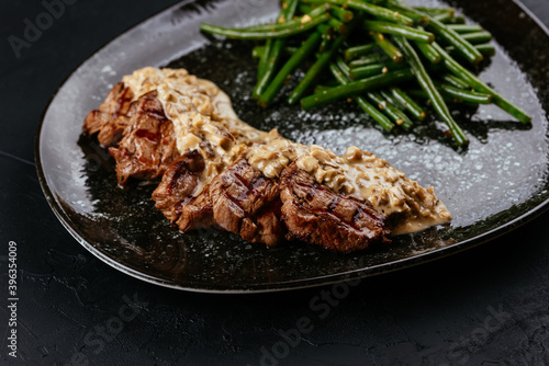 marbled beef steak with vegetables and sauce on a black backgrou photo