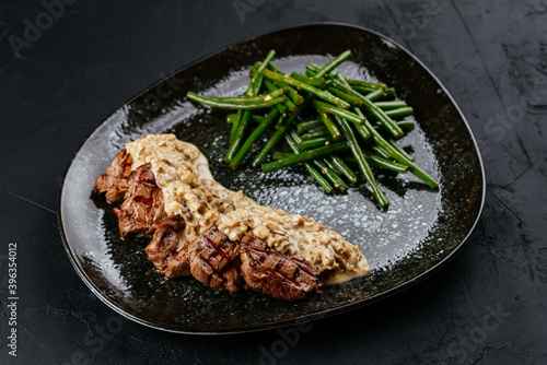 marbled beef steak with vegetables and sauce on a black backgrou photo