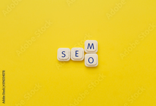 SEM or SEO words made with letters of a board game, over a yellow background. Search engine concepts photo