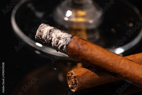 Burning cigar against black background close up