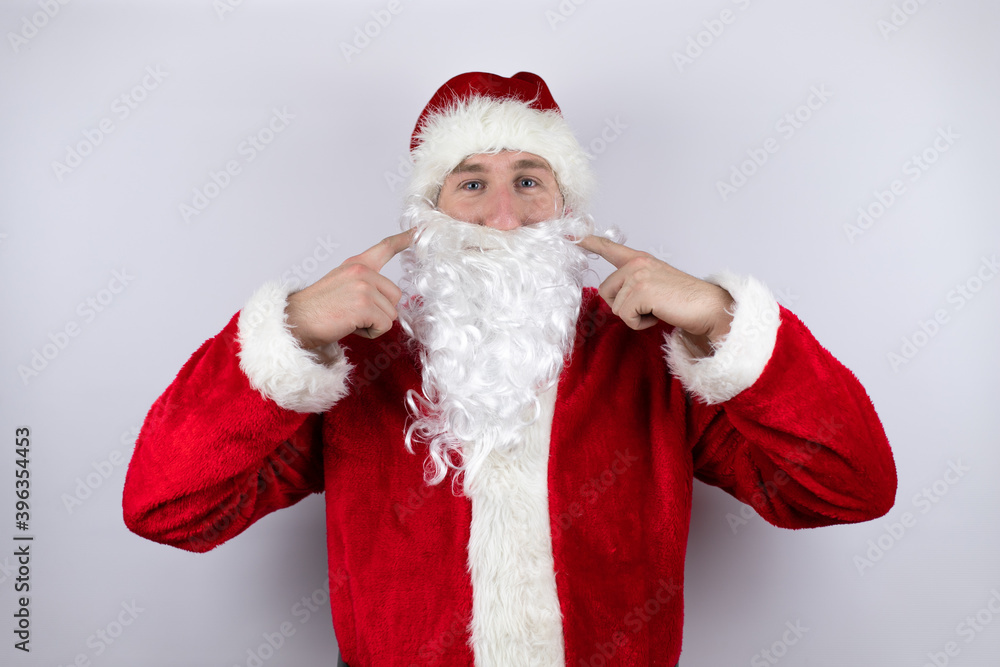 Man dressed as Santa Claus standing over isolated white background smiling confident showing and pointing with fingers teeth and mouth Man dressed as Santa Claus standing over isolated white background smiling confident showing and pointing with fingers teeth and mouth