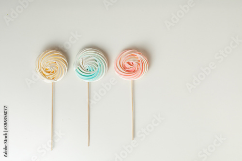 meringue or beze cookies with a wooden stick on the white background