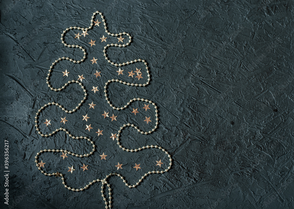 Gold decoration in the form of a Christmas tree on a black background.Place for signature. Gold decoration in the form of a Christmas tree on a black background.Place for signature.